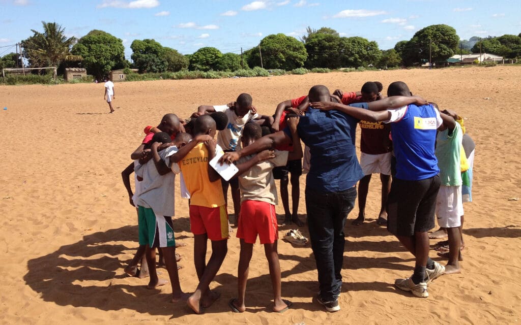 af mozambiqe-praying before playing football on a dirt field