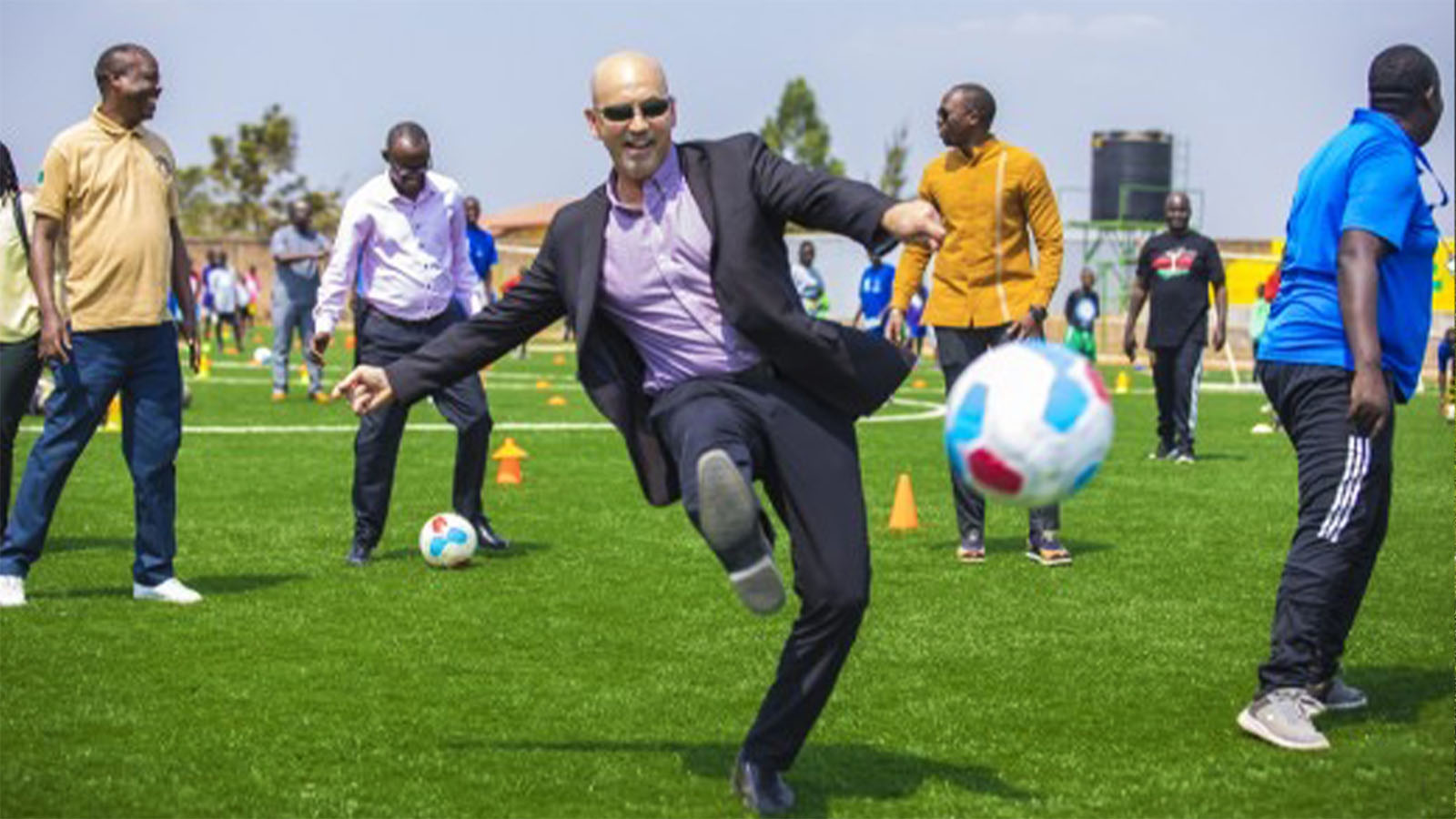 jon ortlip kicking a soccer ball in a suit