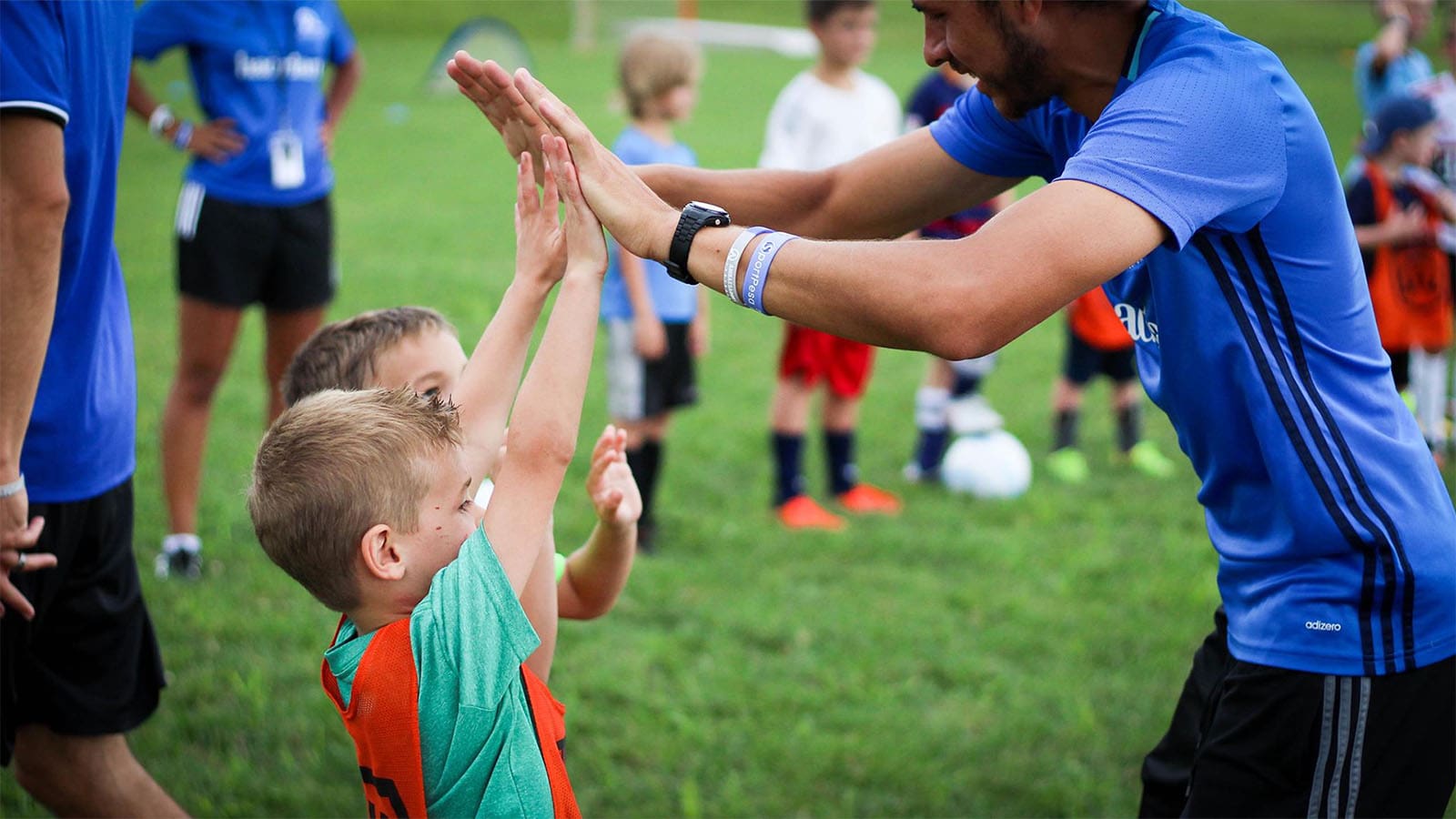 young kids high fiving their soccer coach